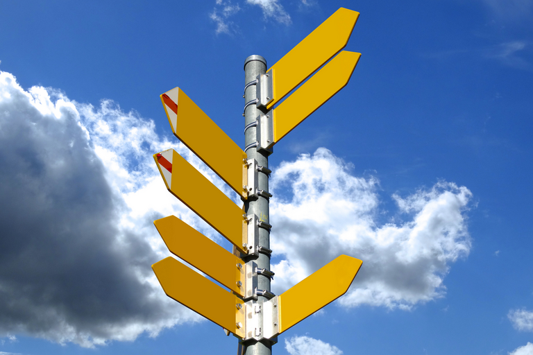 A signpost with yellow signs pointing in many different directions