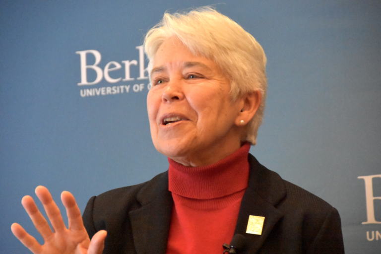 Chancellor Christ speaking, her eyes are looking to the left of the camera, she is gesturing with one hand