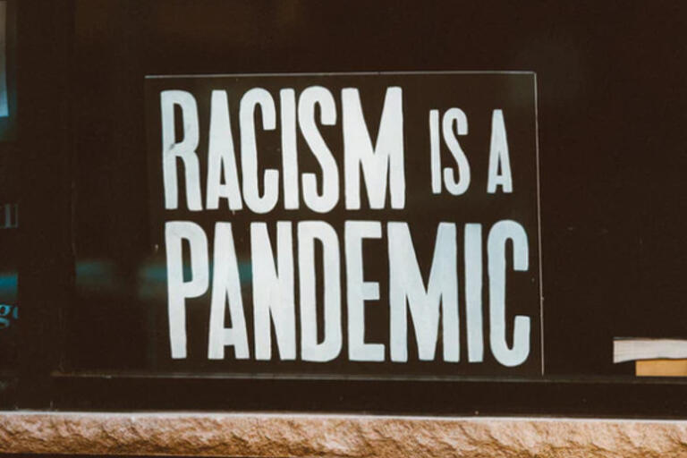 Image of a sign that reads Racism is a Pandemic