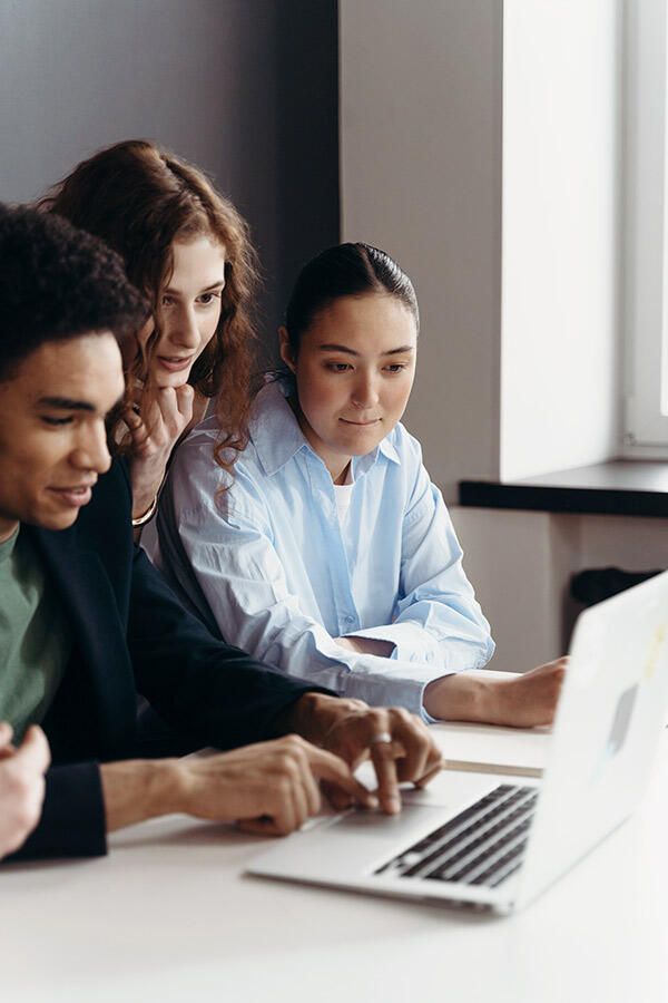 Colleagues sit together looking over a laptop.